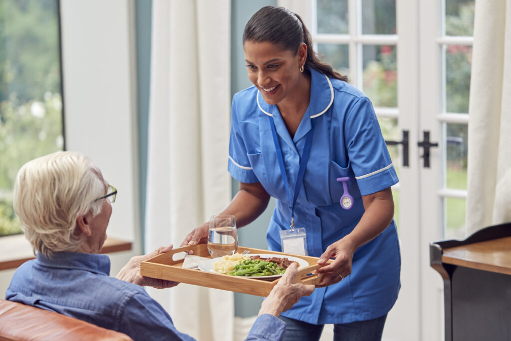 female-care-worker-in-uniform-bringing-meal-on-tray